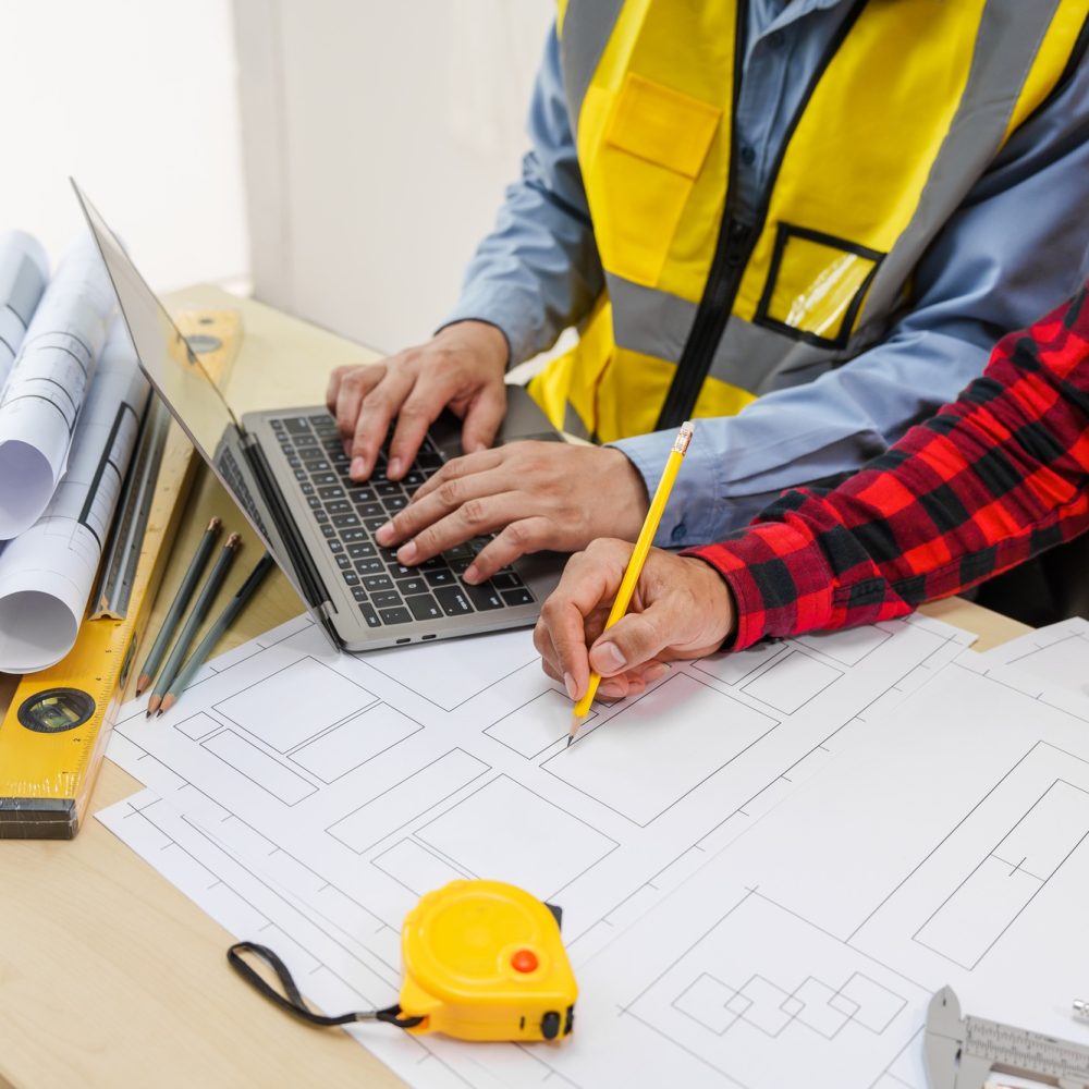 Two men, including a male Asian construction contractor engineer, discuss structural plans